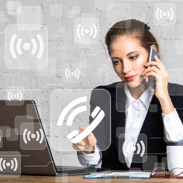 1-voip business service laptop on desk young woman talking on smartphone wifi signs touching call button 